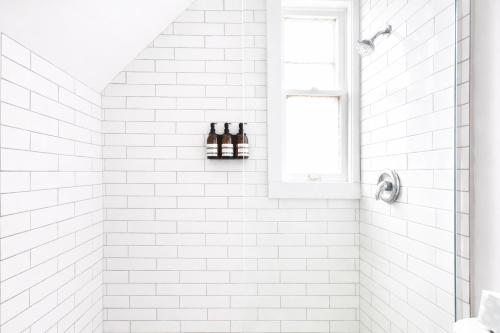 a white tiled shower with two bottles on a shelf at The Santiago Yale New Haven with Parking and Modern in New Haven