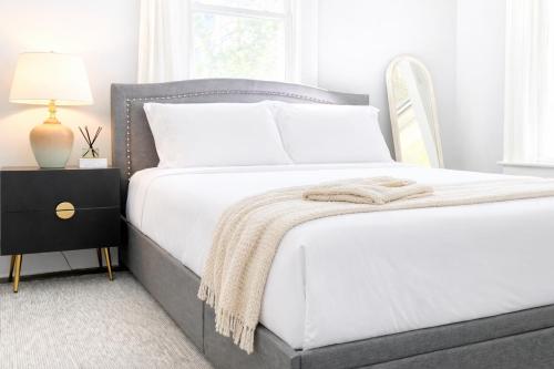 a bedroom with a bed with white sheets and a lamp at The Santiago Yale New Haven with Parking and Modern in New Haven