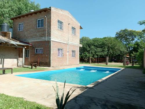 a swimming pool in front of a brick building at Cabaña Doña Adela in Paso de la Patria