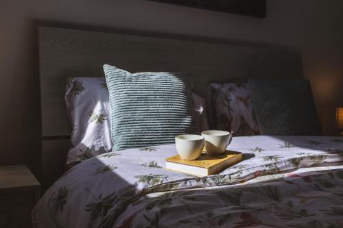 a bed with two books and two cups on it at Luxury Parkside Living Near The 3 Cities in Malta in Tal-Ħamra