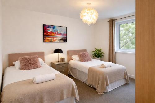 a bedroom with two beds and a chandelier at Blueberry Tree Apartment with Free Parking & Near Station in Cambridge