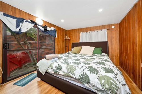 a bedroom with a bed and a large window at Relax Refresh Rejuvenate Pool Cabin Garden Tree house Vintage charm in Berwick