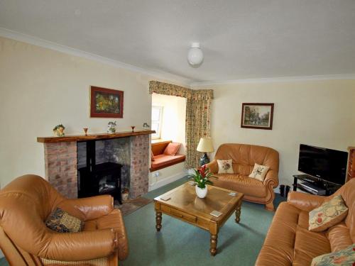 a living room with leather furniture and a fireplace at Coelard Farmhouse - Usj in Appin