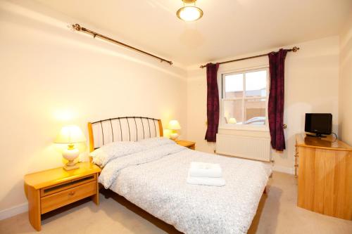 een slaapkamer met een bed, een tv en een raam bij Leamington Spa Apartments in Leamington Spa