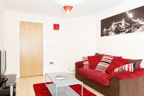 a living room with a red couch and a table at Leamington Spa Apartments in Leamington Spa