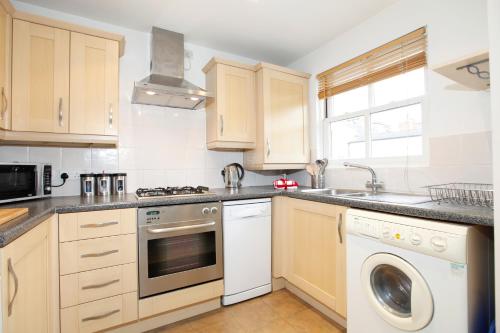 a kitchen with wooden cabinets and a washer and dryer at Leamington Spa Apartments in Leamington Spa