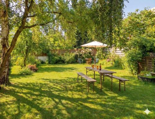 a table and benches in a yard with an umbrella at Rhein River Guesthouse - direkt am Rhein in Leverkusen