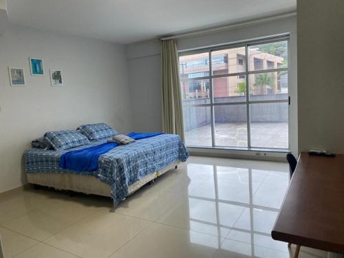 a bedroom with a bed and a large window at 115 - Saint Sebastian Flat in Jaraguá do Sul