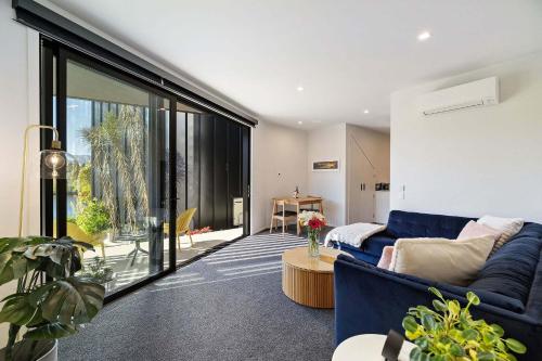 a living room with a blue couch and a large window at Haven on the Lake Front in Frankton