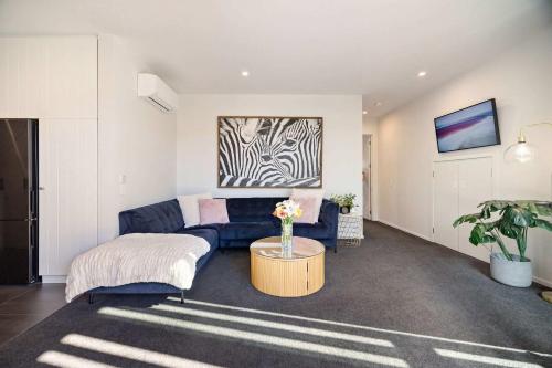 a living room with a blue couch and a table at Haven on the Lake Front in Frankton