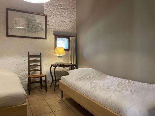 a bedroom with a bed and a chair and a lamp at Domaine Voilà in Génis
