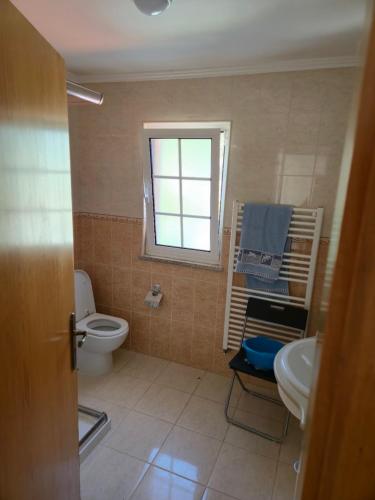 a bathroom with a toilet and a sink and a window at Casa 3 quartos - Outeiro do Sul in Adopisco