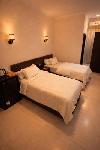two beds in a hotel room with white sheets at Zaytun Hotel Dahab in Dahab