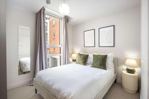 a white bedroom with a bed and a window at 5 Mins Walk to Moorgate, Tranquil City Retreat in London