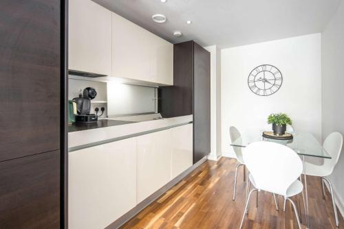 a kitchen with white cabinets and a table and chairs at 5 Mins Walk to Moorgate, Tranquil City Retreat in London