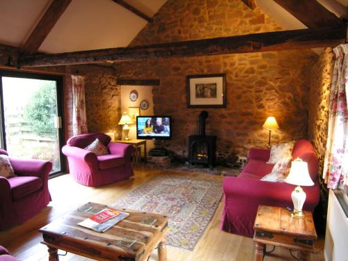a living room with purple furniture and a stone wall at Stables- Ukc4912 in Timberscombe