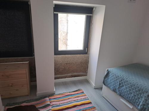 a bedroom with a bed and a window and a rug at Casa da Figueira in Aguiar da Beira