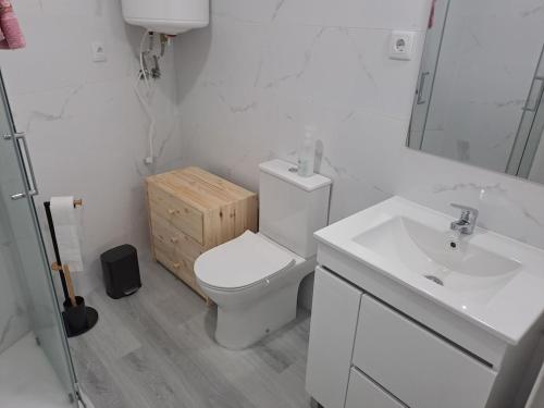 a white bathroom with a toilet and a sink at Casa da Figueira in Aguiar da Beira