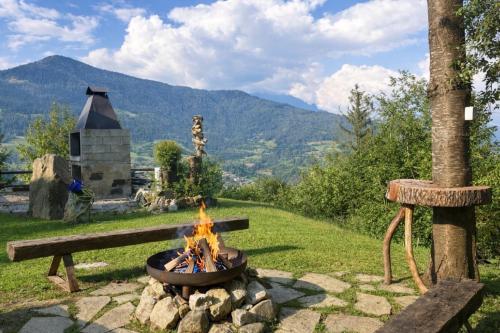 a fire pit with a bench and mountains in the background at Baita immersa nella natura in Borno
