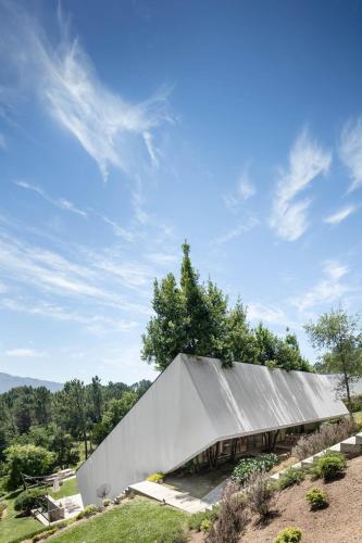 a building with a metal roof on top of a field at Slope Design Villa - Architecture villa with private pool in Ponte de Lima