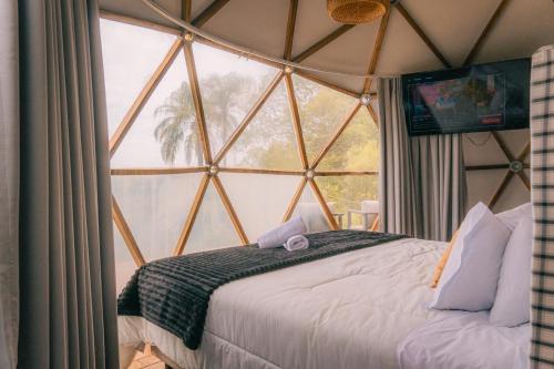 a bed in a room with a large window at Monakó Cabanas in Bragança Paulista