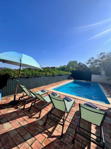 a group of chairs and an umbrella next to a swimming pool at Casa da Parreira in Loulé