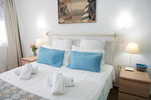 a bedroom with a white bed with blue and white pillows at Rania Bella Vista Studios in Poros
