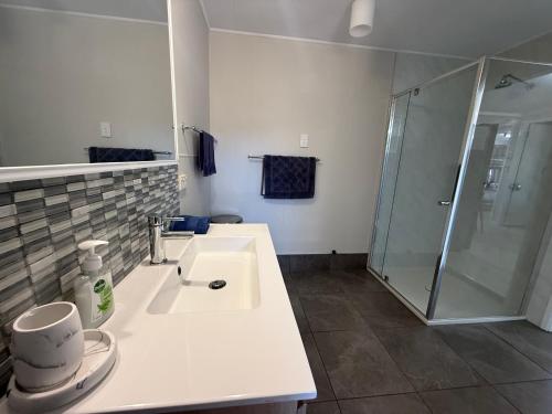 a white bathroom with a sink and a shower at Hideaway on King in Urangan