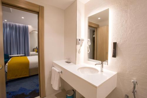 a bathroom with a sink and a mirror and a bed at Hotel Carlton in Tunis