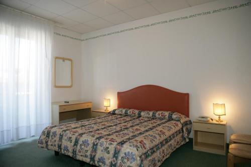 a hotel room with a bed and two tables and two lamps at Hotel Villa Rosa in Grado
