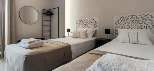a white bedroom with two beds and a mirror at Niki`s Luxury Apartment in Makry Gialos