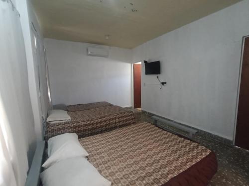 two beds in a small room with a tv at Casa Emilio Carranza, Linares in Linares