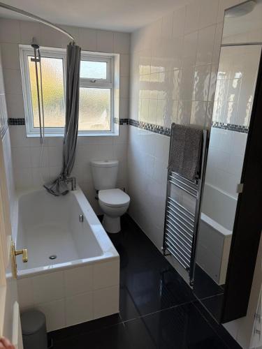 a bathroom with a tub and a toilet and a sink at New Forest Home in Hordle