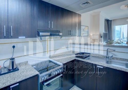 a kitchen with wooden cabinets and a sink and a stove at Staymora Suites in Dubai