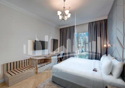 a white bedroom with a bed and a desk at Staymora Suites in Dubai