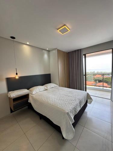a bedroom with a bed and a large window at STUDIO CALHAU 907 Vista mar in São Luís