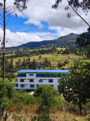 a white building with a blue roof in a field at Hotel Alta Montaña Mongui By Seres Viajeros in Monguí