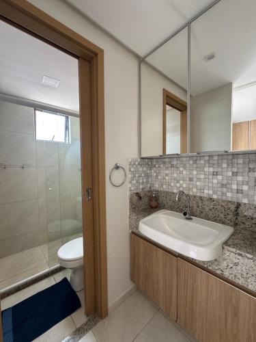 a bathroom with a sink and a toilet and a mirror at STUDIO CALHAU 907 Vista mar in São Luís
