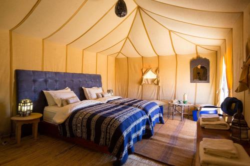 a bedroom with a large bed with a pointed ceiling at Merzouga Retreat Camp in Merzouga