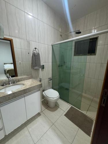 a bathroom with a toilet and a glass shower at Alvorada Hospedagem in Jataí