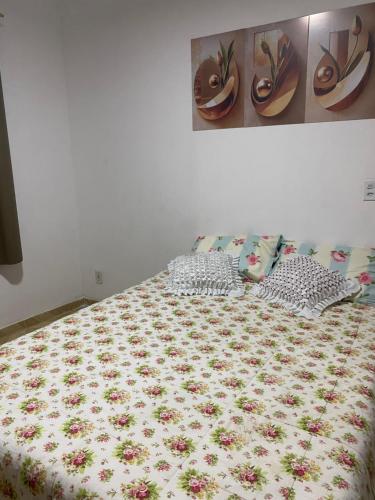 a bed with a floral bedspread and pillows on it at Casa dá Jo in Rio das Ostras