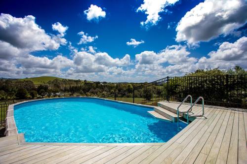a swimming pool with a wooden deck and a blue sky at The Shack in Mangonui