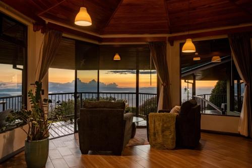 a living room with two chairs and a balcony at Hotel Trópico Monteverde in Monteverde Costa Rica