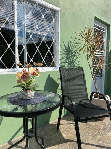 a table and a chair with a vase of flowers at Condomínio Central Sobradinho in Uruguaiana