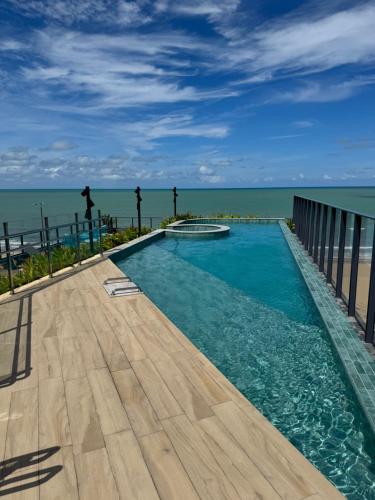 a swimming pool with the ocean in the background at Garden Haus - Flat beira mar in João Pessoa