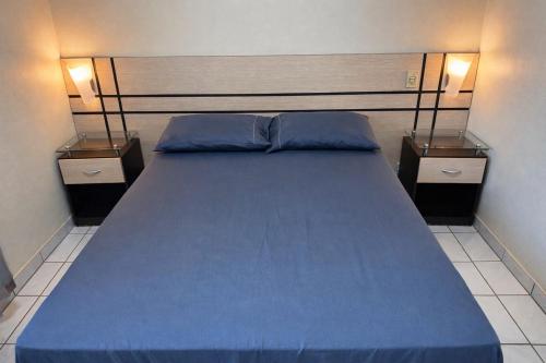 a bedroom with a blue bed with two night stands at Apto Aquarius - Piscinas Aquecidas, Hidro e Lazer Total - até 5 Pessoas in Caldas Novas