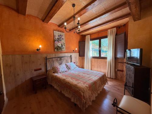 una camera da letto con un letto e una televisione di Paraje el Serbal a Benatae