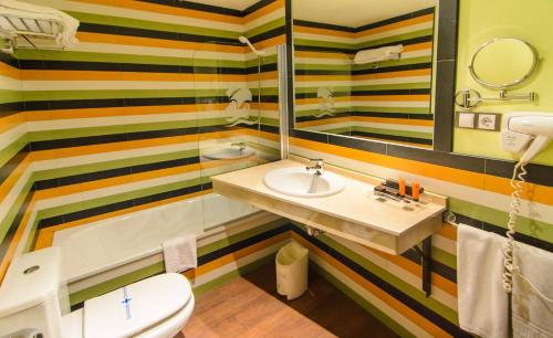 a bathroom with a sink and a toilet and a mirror at Hotel Apartamento Martín Alonso Pinzón in Mazagón