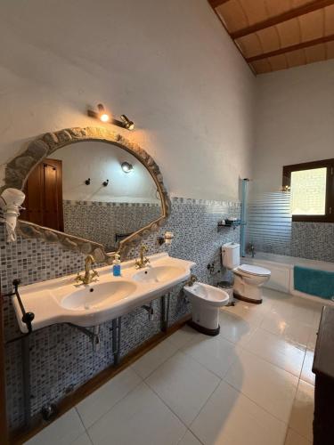 un bagno con due WC, un lavandino e uno specchio di Paraje el Serbal a Benatae