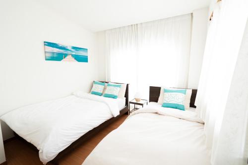 two beds in a room with a window at Yotsugi House 3rd Floor - Prime Location Near Asakusa and Skytree in Tokyo